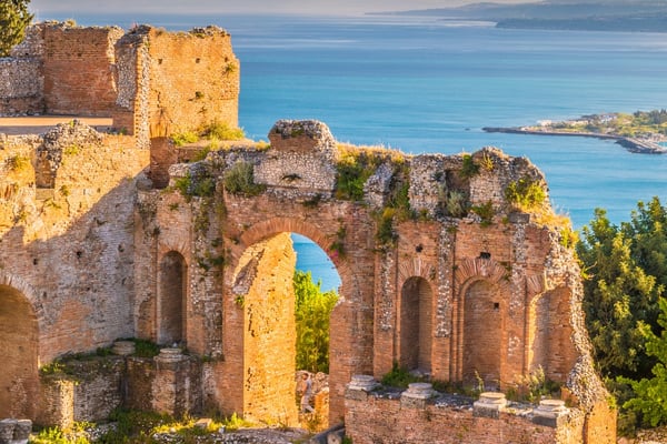 Panoramic view of the Ancient Theatre of Taormina overlooking the Ionian Sea and the Sicilian coastline.