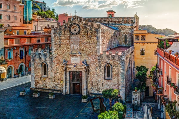 The medieval Church of San Niccolò di Bari in Taormina, surrounded by colorful historic buildings and charming streets.